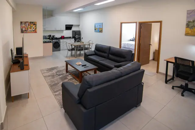 Living con sillones y cocina integrada del departamento para seis
