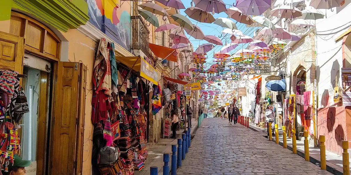 Calle del Mercado de las Brujas con puestos de tejidos y paraguas colgados